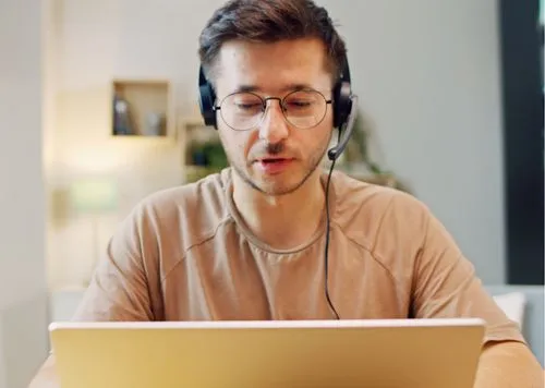 A person wearing headphones and looking at a laptop