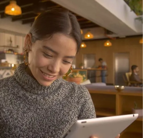 A person smiling while holding a tablet