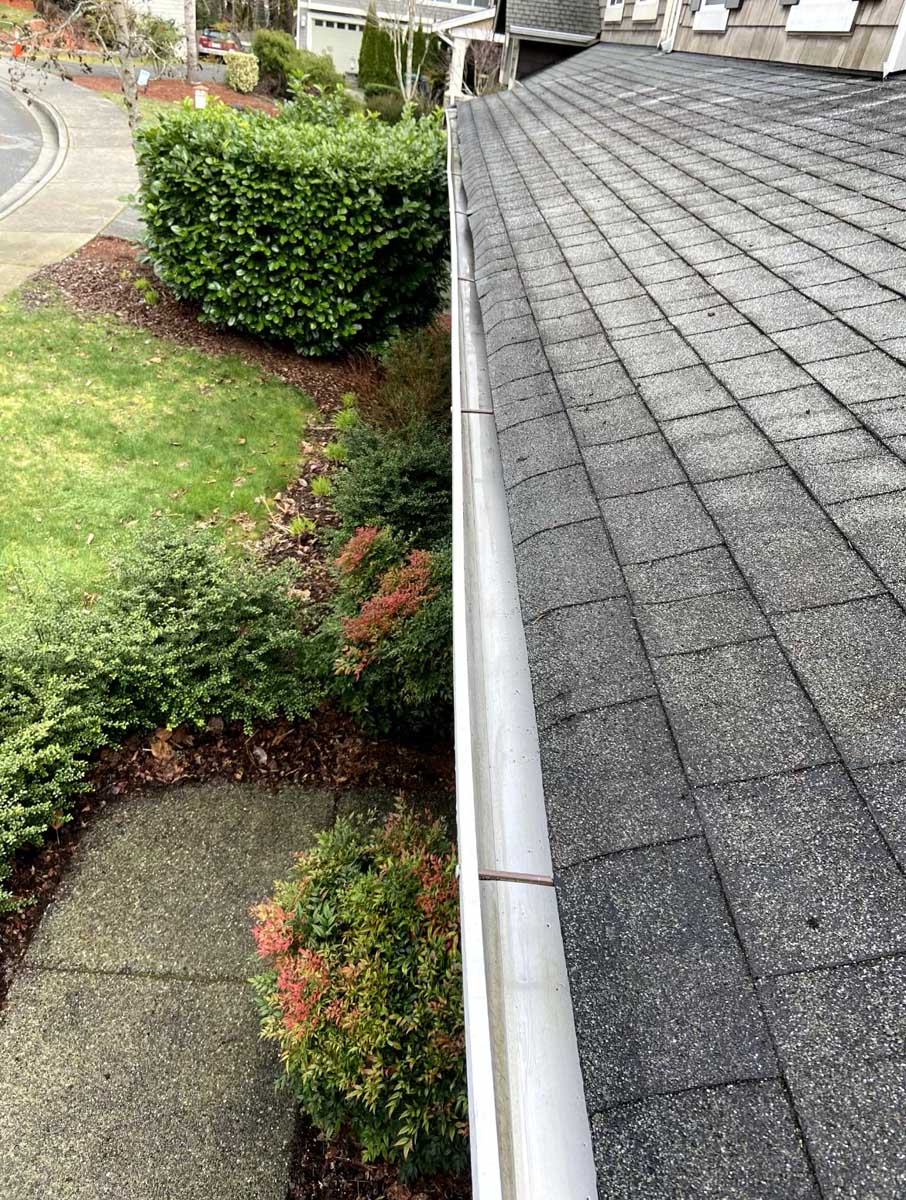View of clean gutters above a patio and shrub