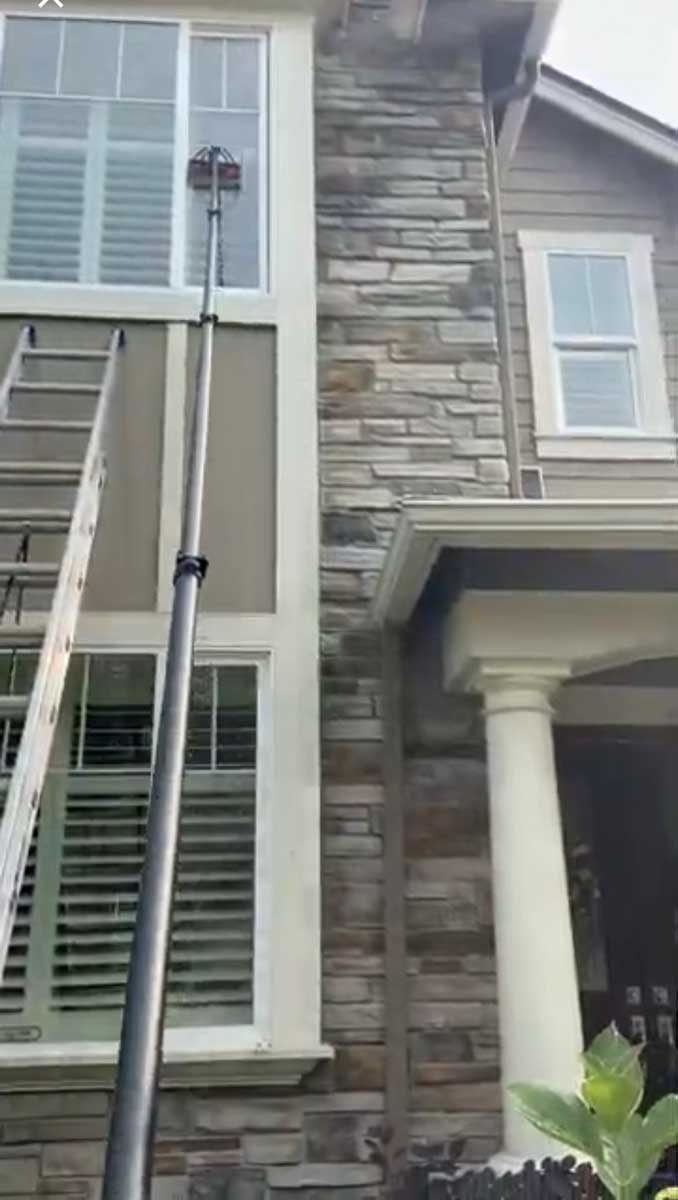 High windows on home being cleaned with specialty equipment.