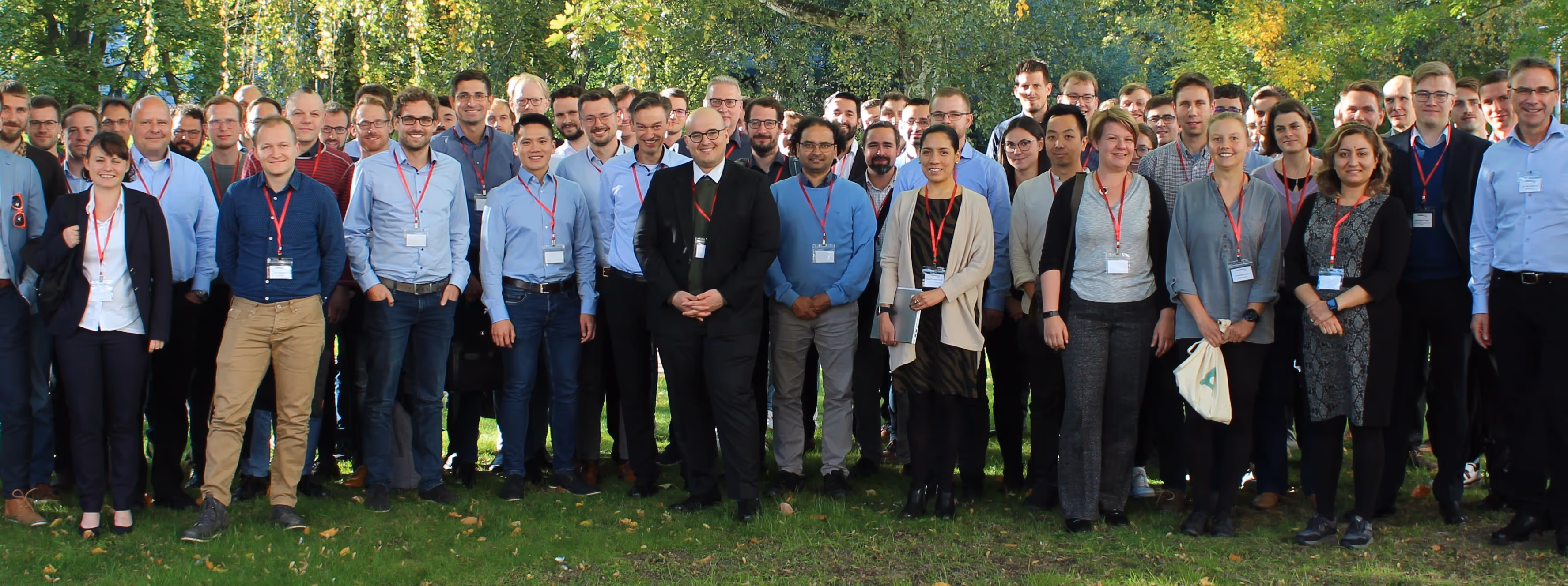 Outdoor seating area with red umbrellas and metal tables in front of a brick building with large arched windows and a sign reading La Fabrik.