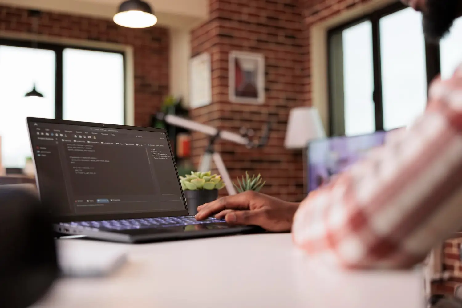 Developer working on a laptop with website code displayed on screen.
