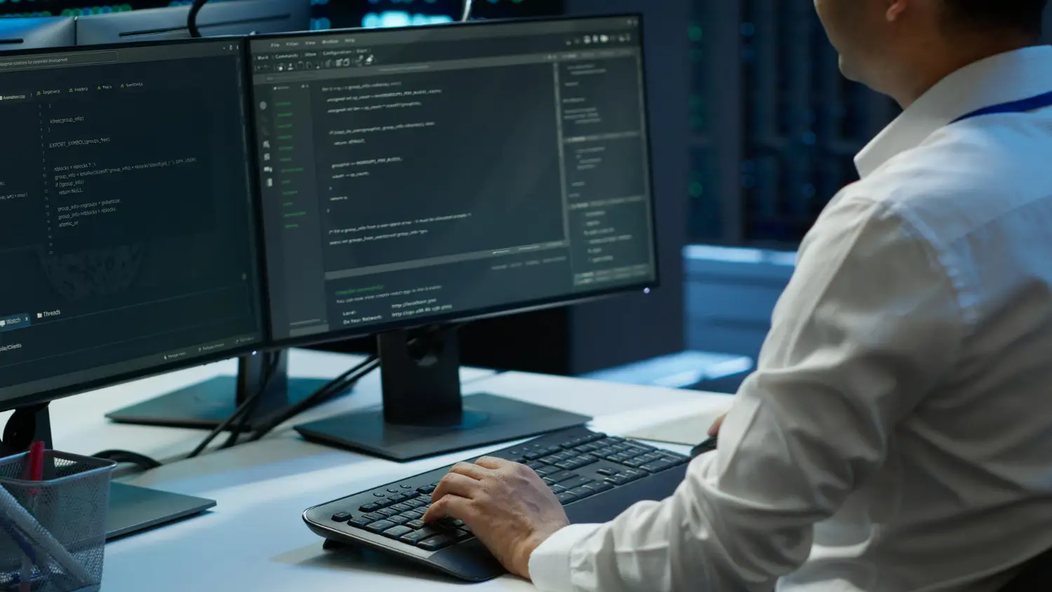 Developer working on software code using dual monitors