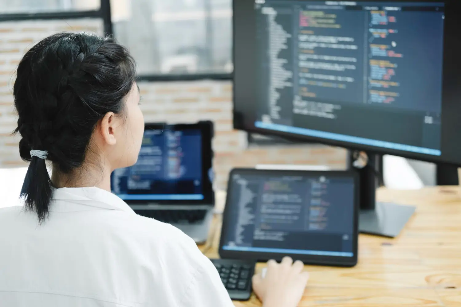 Website development and technical support with code displayed across multiple monitors