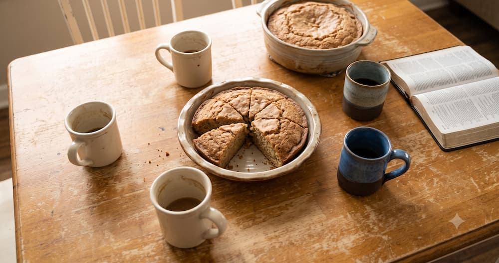 Overhead view of homemade coffee cake and coffee mugs set out for a church small group gathering
