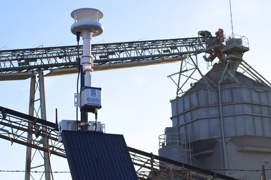 Solar-powered outdoor air quality sensor system featuring the Dust Module for industrial dust monitoring and PM10 air quality measurement, shown measuring dust in front of a construction site; the best PM10 monitoring option available.