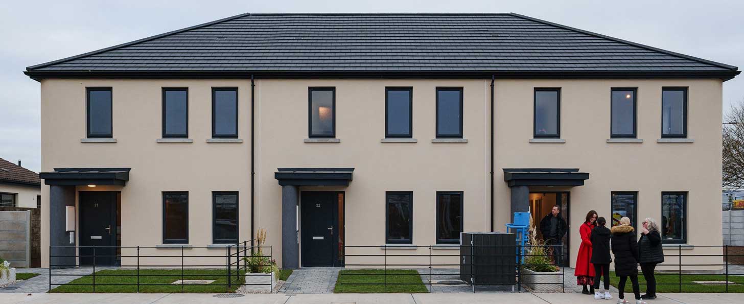 A group of people stands outside of the Grange Close development in Dundalk, Ireland