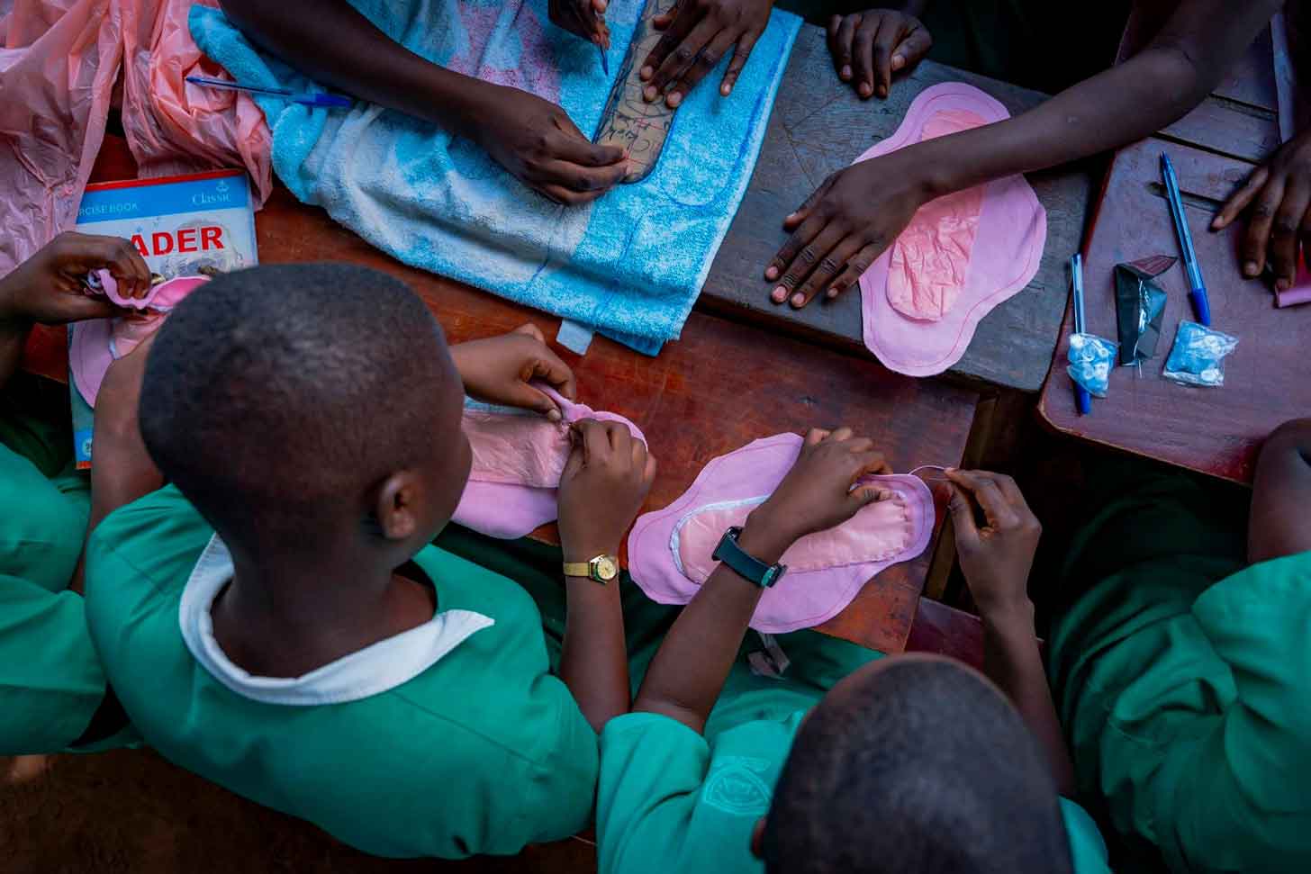 An aerial view of young girls sewing and assembling reusable menstrual pads in Uganda