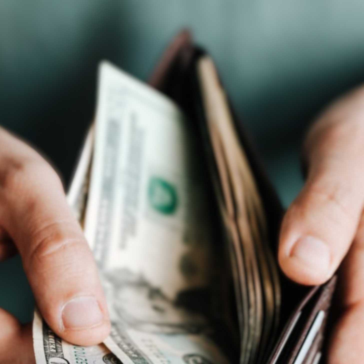 a slightly blurred photo of someone opening a wallet to reveal cash