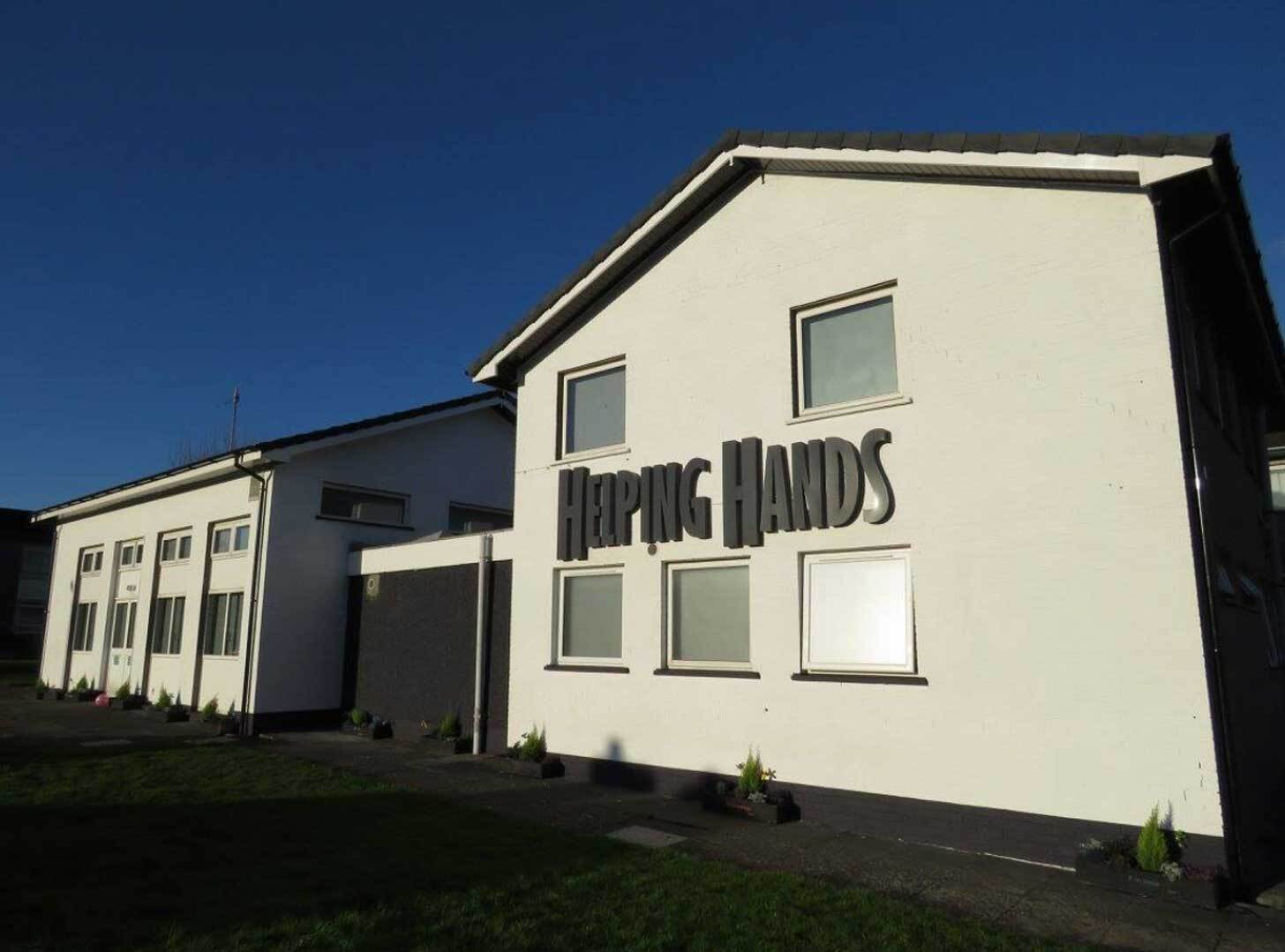 The exterior of the Helping Hands Autism Center in Belfast, Northern Ireland. It is a white building with black trim, with the name of the builiding in large font across the front. 
