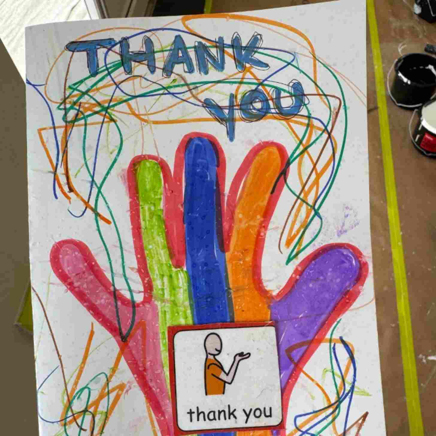A card that says Thank you! With a hand colored in by crayon.