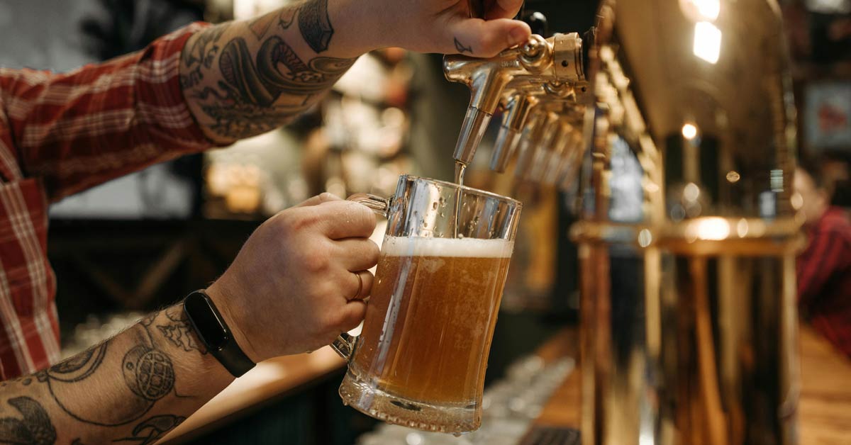 A bartender pours a pint of beer from the tap