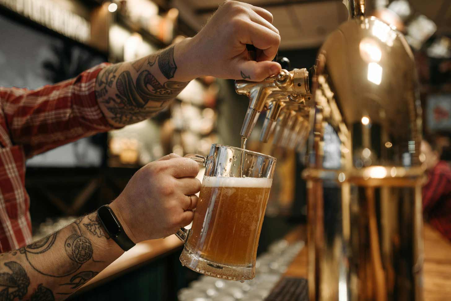 A bartender pours a pint of beer from the tap