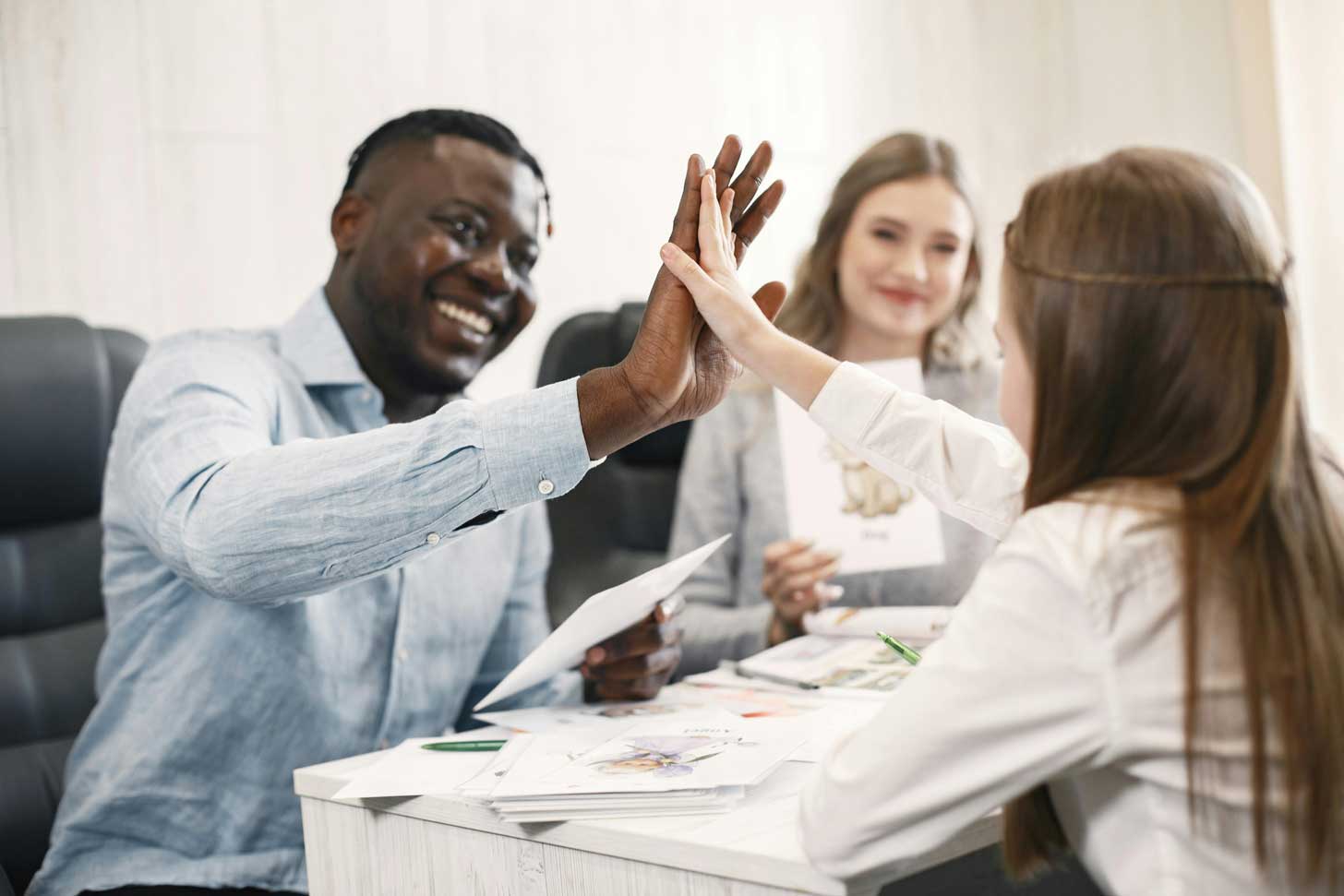 A Black male teacher high-fives a white female student