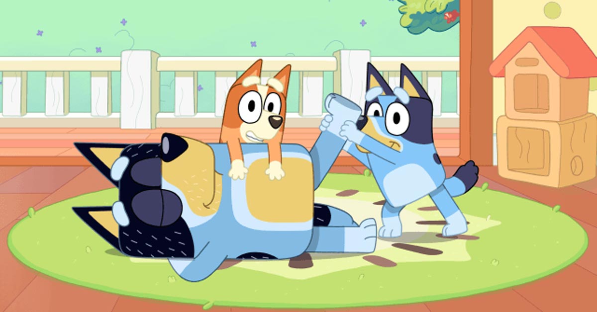A still from the kid's show Bluey, where two small dogs play with one larger dog