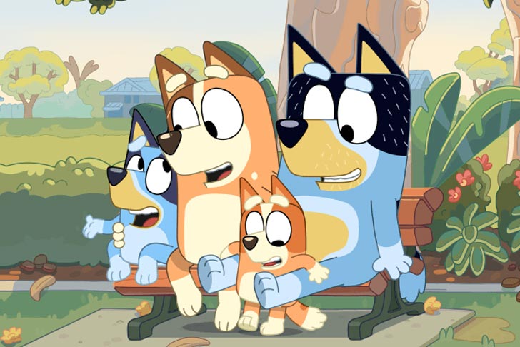 A still from the children's animated tv show "Bluey," showing two parent dogs with their children.