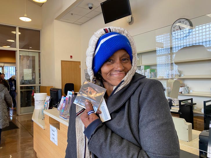 A person experiencing homelessness holds up a library card inside the Los Angeles Public Library
