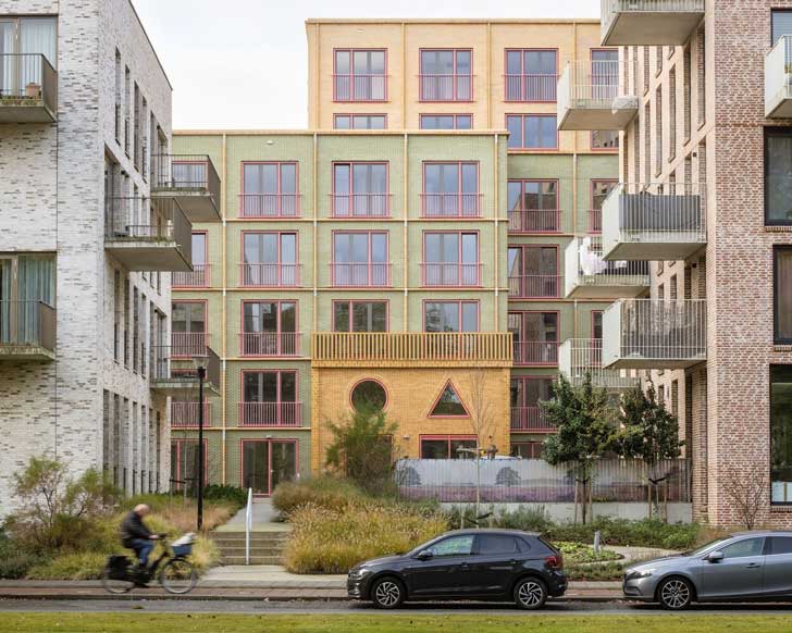 A bright yellow and green building situated between two other brown brick buildings