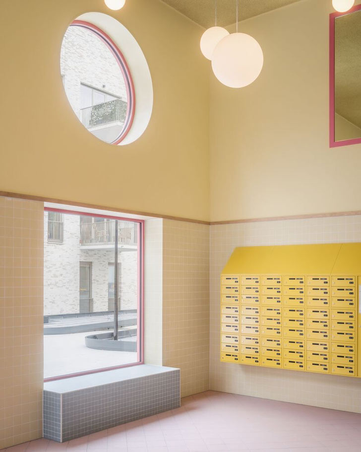A hallway with pastel tiles and yellow mailboxes