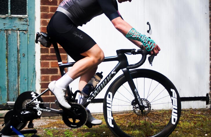 A person on a bike has a turquoise cast on their forearm