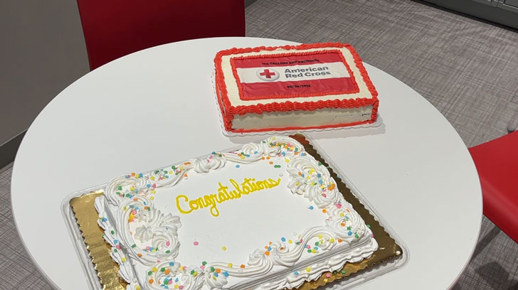 Two sheet cakes on a table, one with yellow icing reading Congratulations, and the other with the American Red Cross logo and red piping