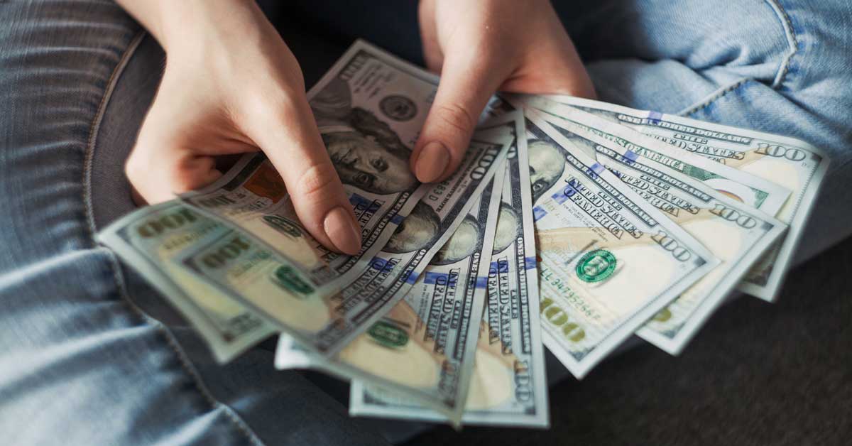 A person fans out ten 100-dollar bills