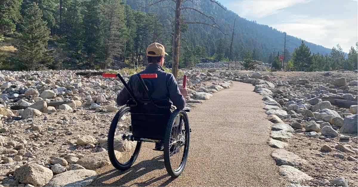 A man in a wheelchair cruises down a trail in Rocky Mountain National Park