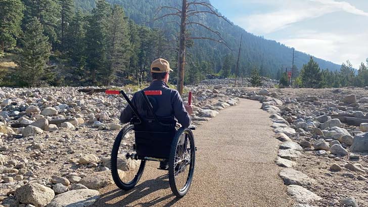 A man in a wheelchair cruises down a trail in Rocky Mountain National Park