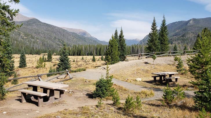 A scenic view of Rocky Mountain National Park with two picnic tables in the foreground