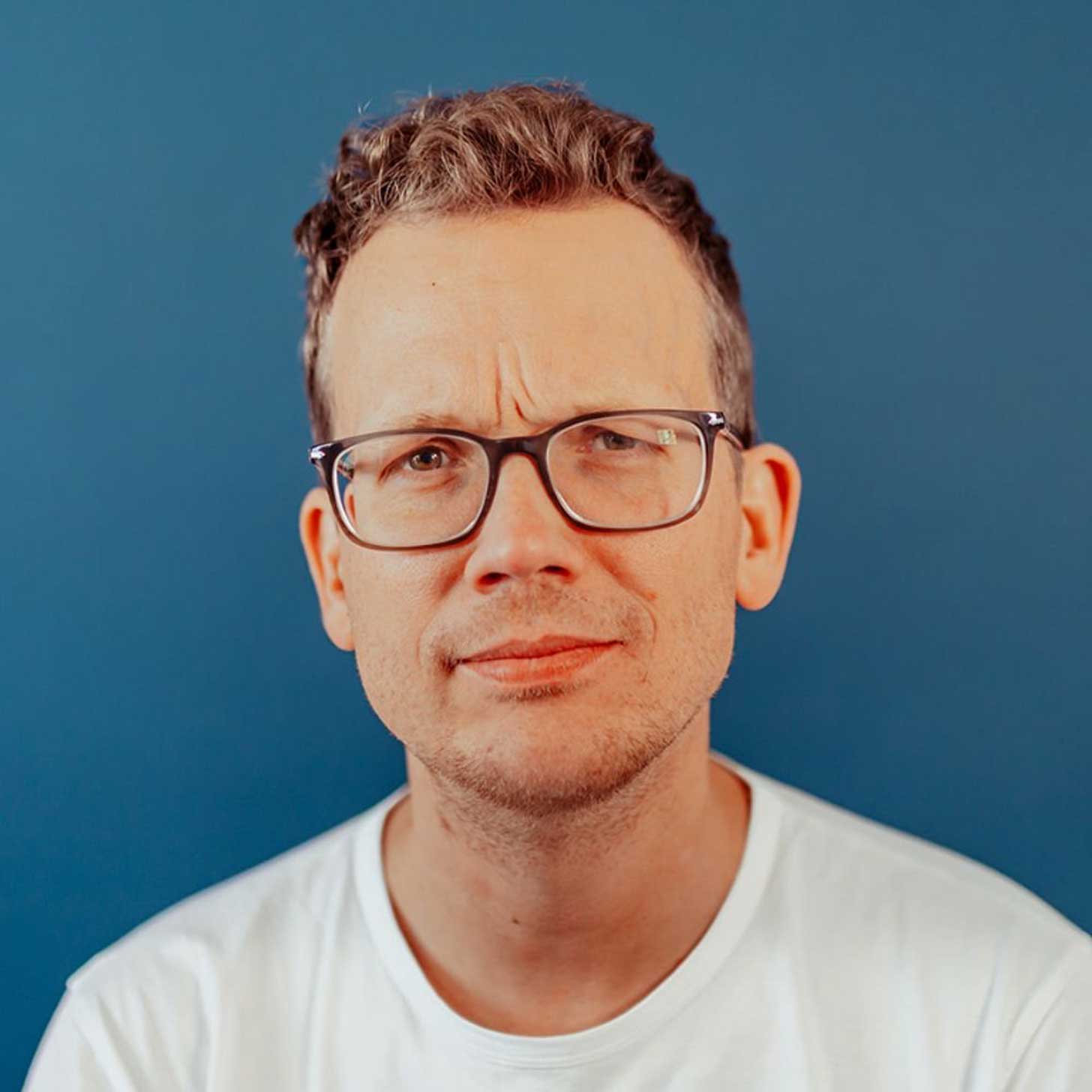 Hank Green poses against a blue background