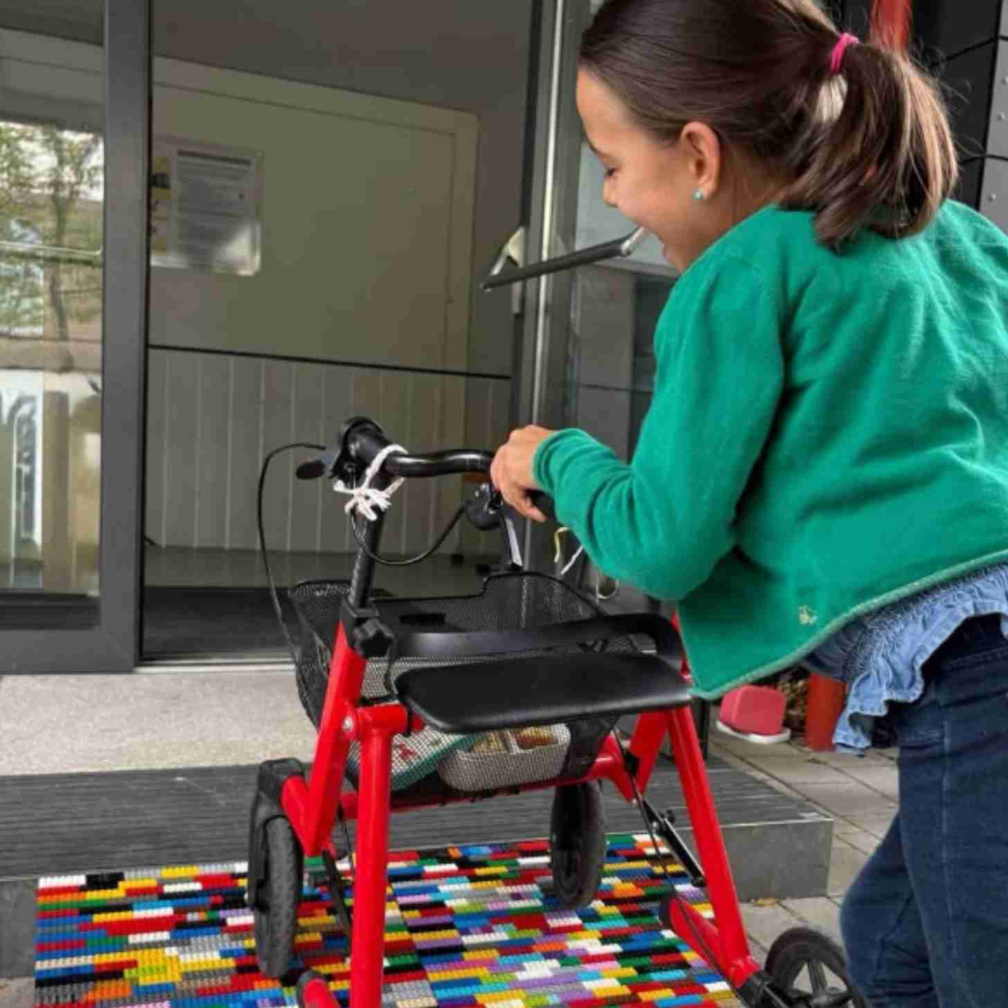 A girl uses a walker to ascend a Lego ramp