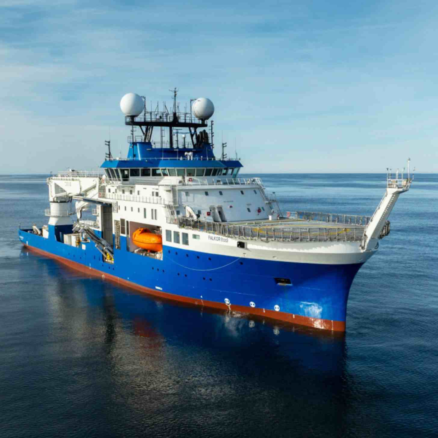 An ship on the open ocean, with clear blue skies overhead. 