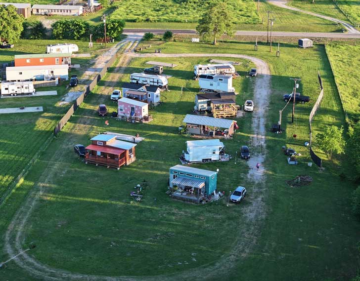 An aerial view of a tiny home neighborhood on a plot of green land in Texas