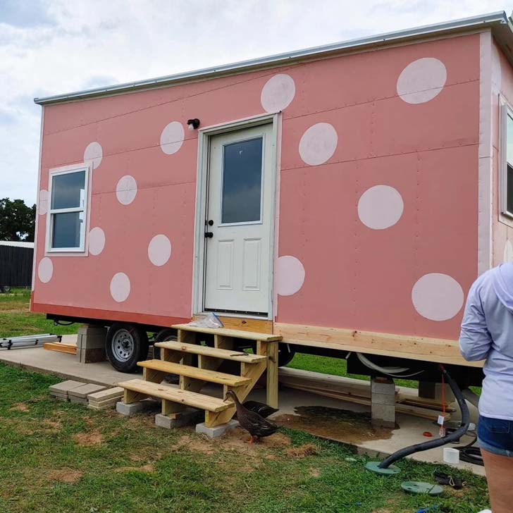 A pink tiny house covered in white polka dots