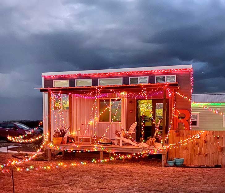 A tiny house covered in red and gold Christmas lights