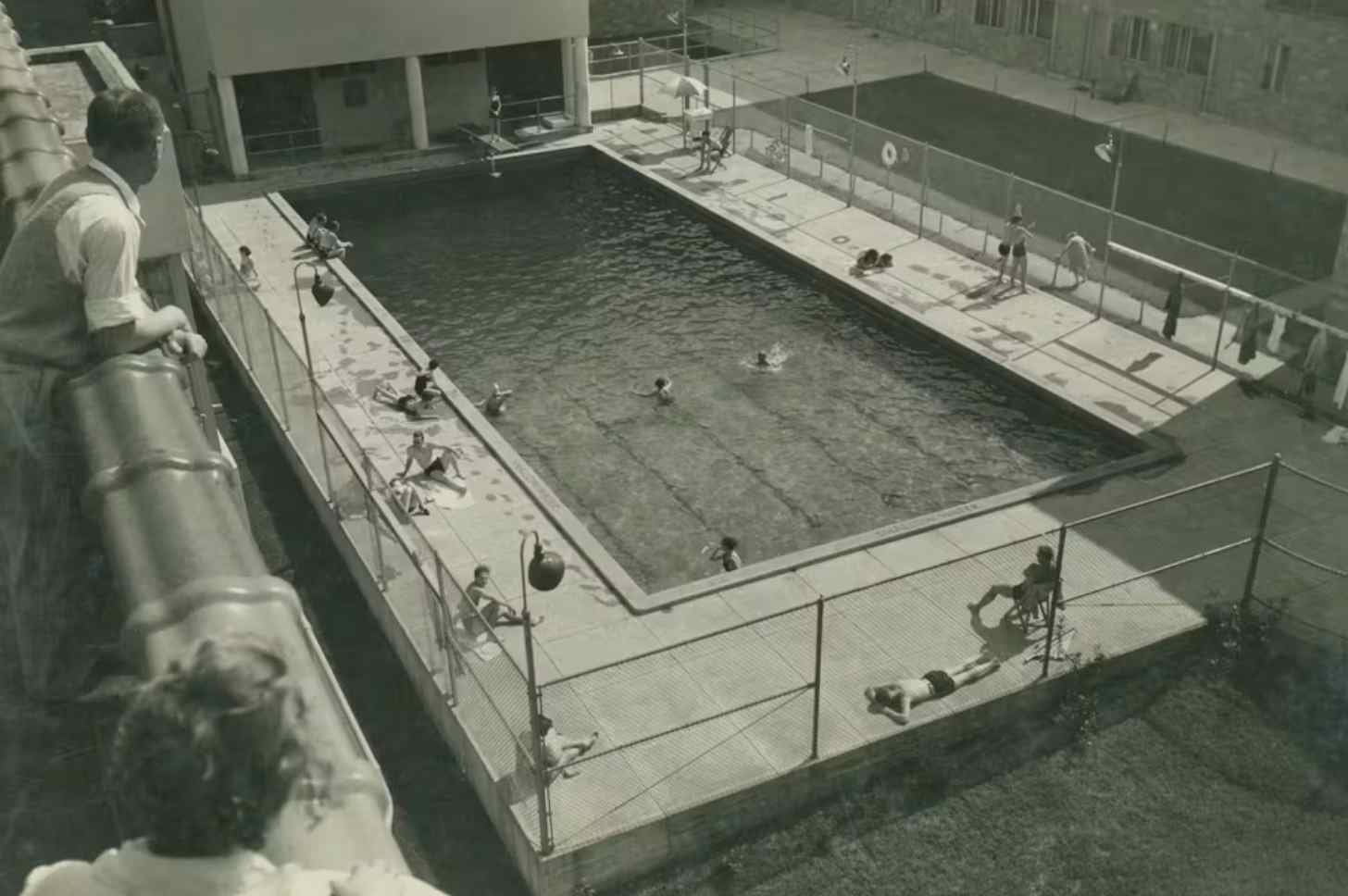 Black and white photo of a swimming pool surrounded by an apartment complex.