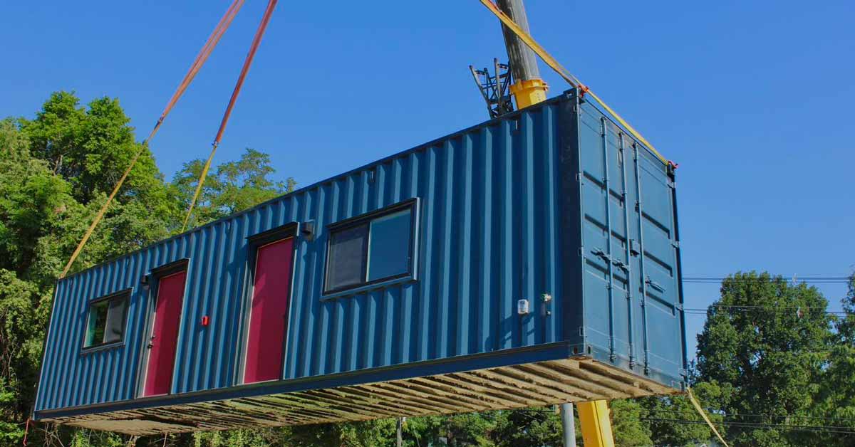 A blue and red shipping container home on a lift
