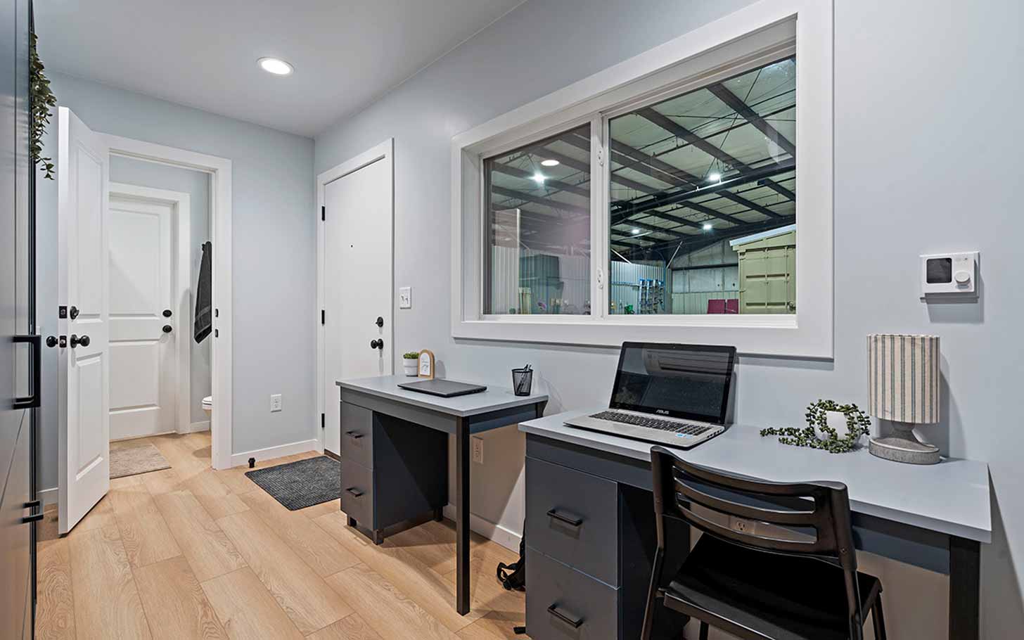 An interior view of a dorm room with two desks overlooking a window
