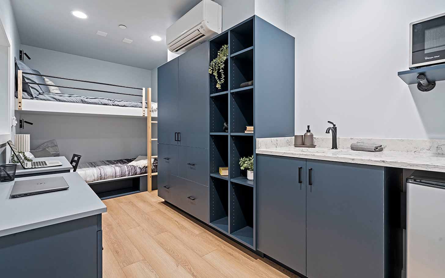 An interior view of a dorm room with dark blue cabinets