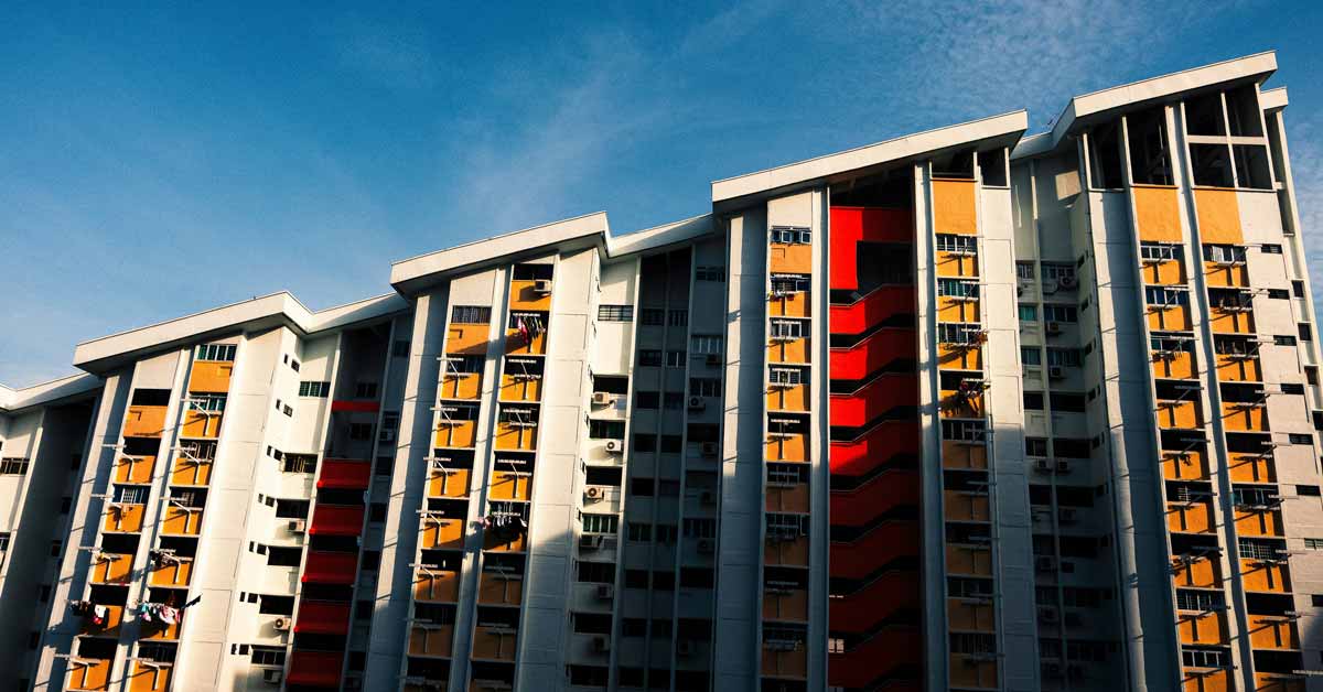 A red, yellow, and white apartment building sits against a blue sky