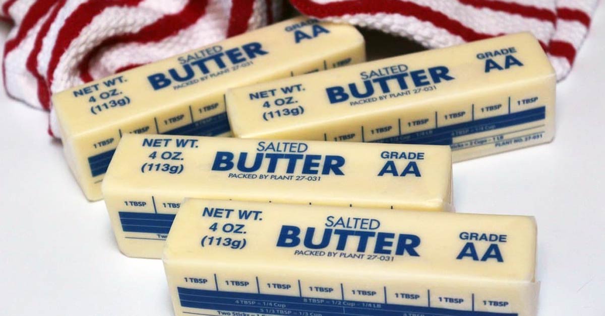 Four sticks of salted butter next to a red and white striped towel