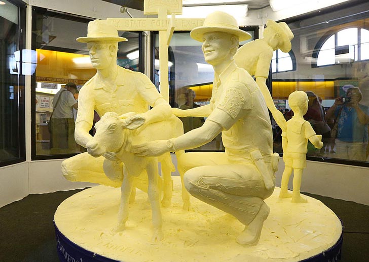 A New York State Fair butter sculpture of two men next to a small cow
