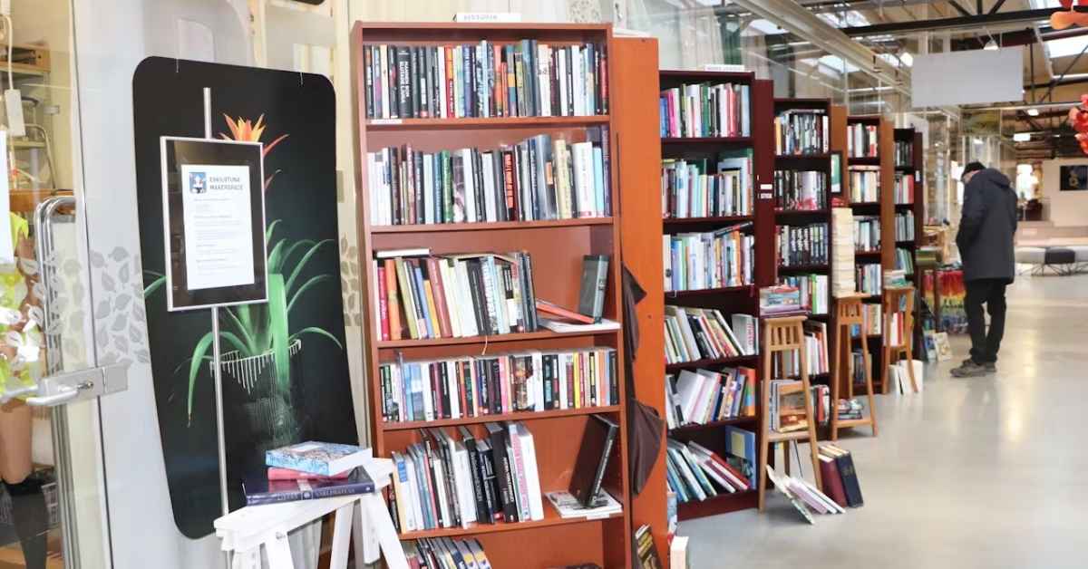 Multiple bookshelves are found inside a store, with a lone man browsing an aisle