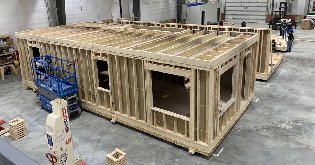 The frame of a house sits inside of a construction factory