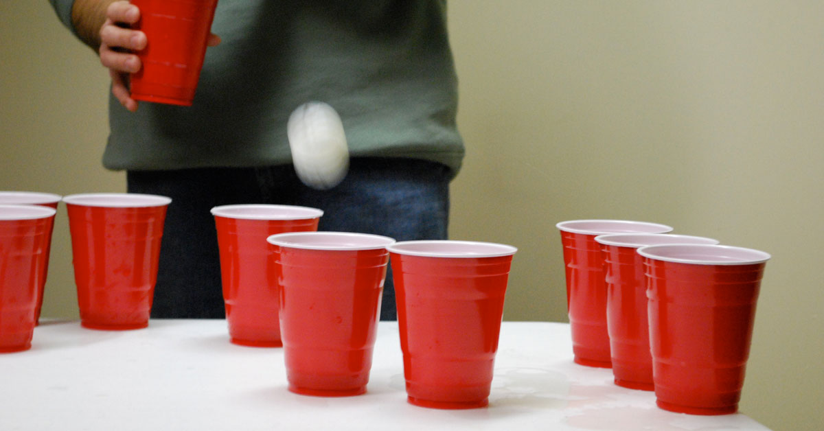 A ping pong ball bounces in a pyramid of red and white party cups