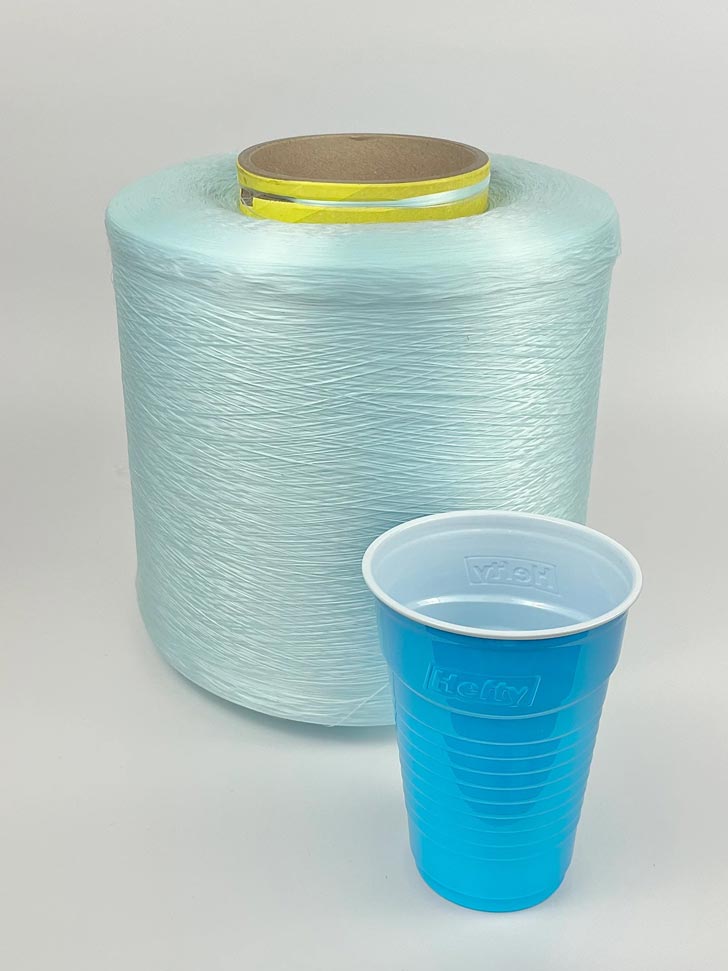 A large skein of light blue yarn sits next to a blue party cup