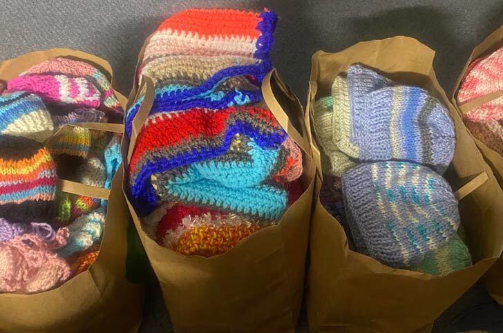 bags full of knitted baby clothes, sweaters, blankets hats