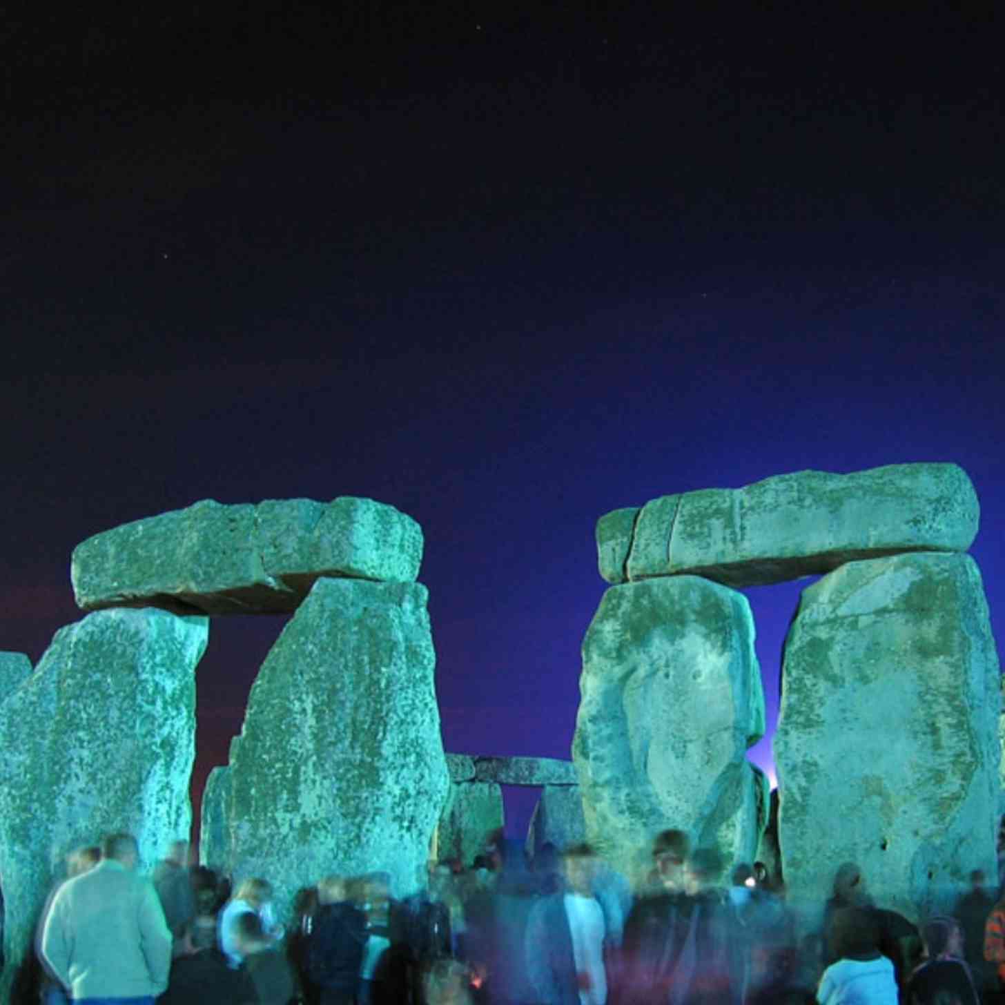 Stonehenge at night, with a crowd of people blurring past