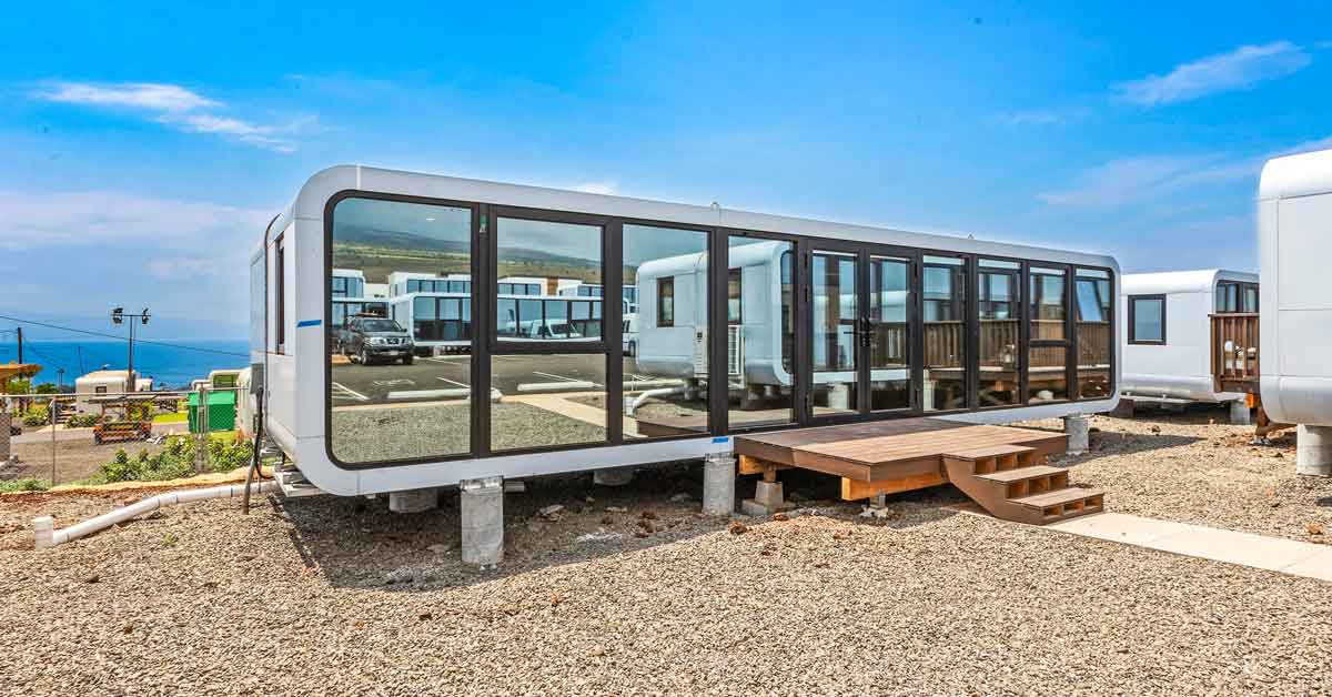 A modular tiny home sits on planks in a village in Hawaii