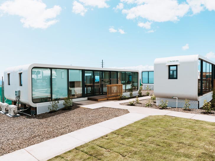 Two white modular tiny homes sit next to each other in a community in Hawaii